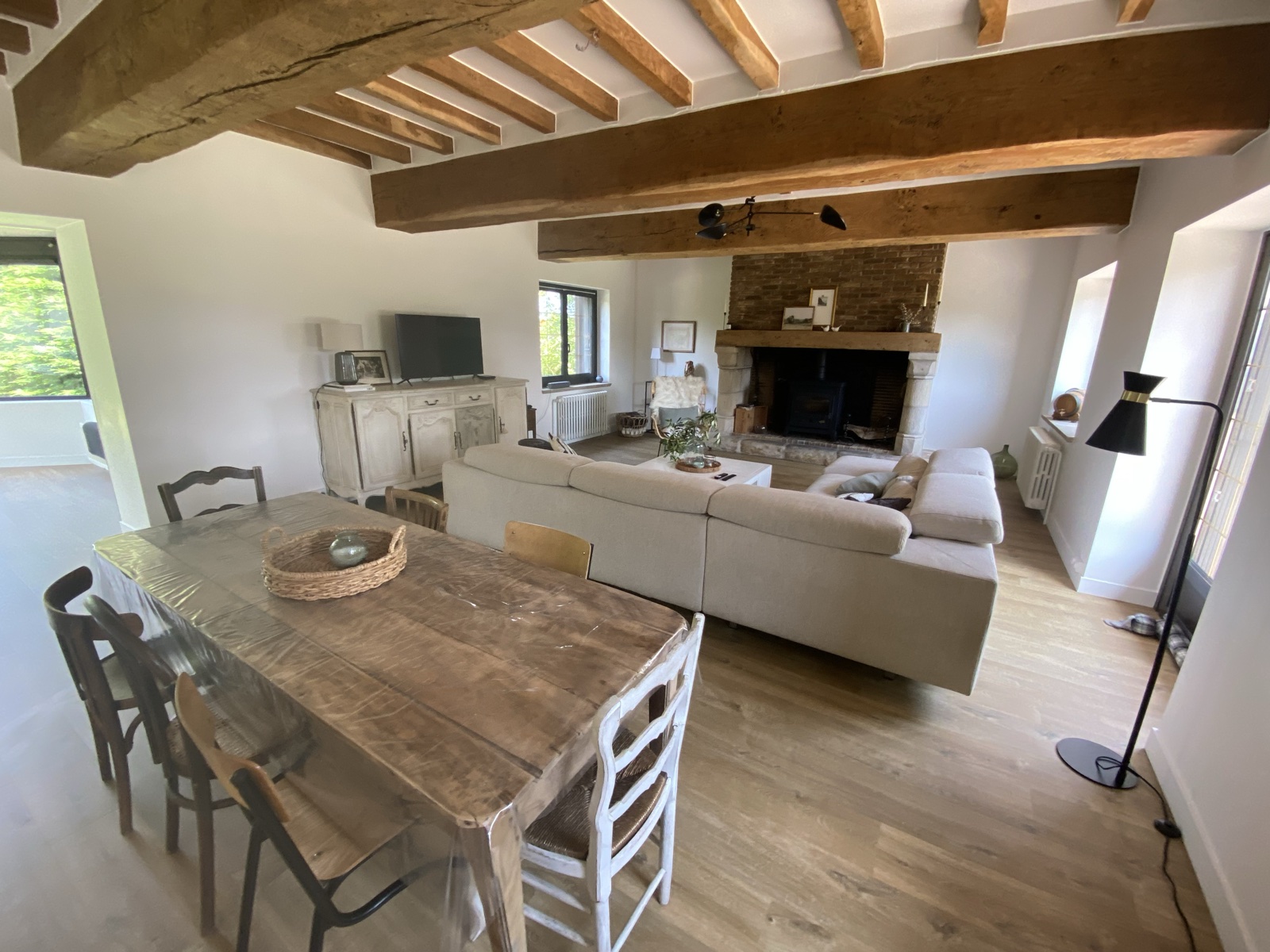 Open-plan salon with beamed ceiling, fireplace and farmhouse dining table