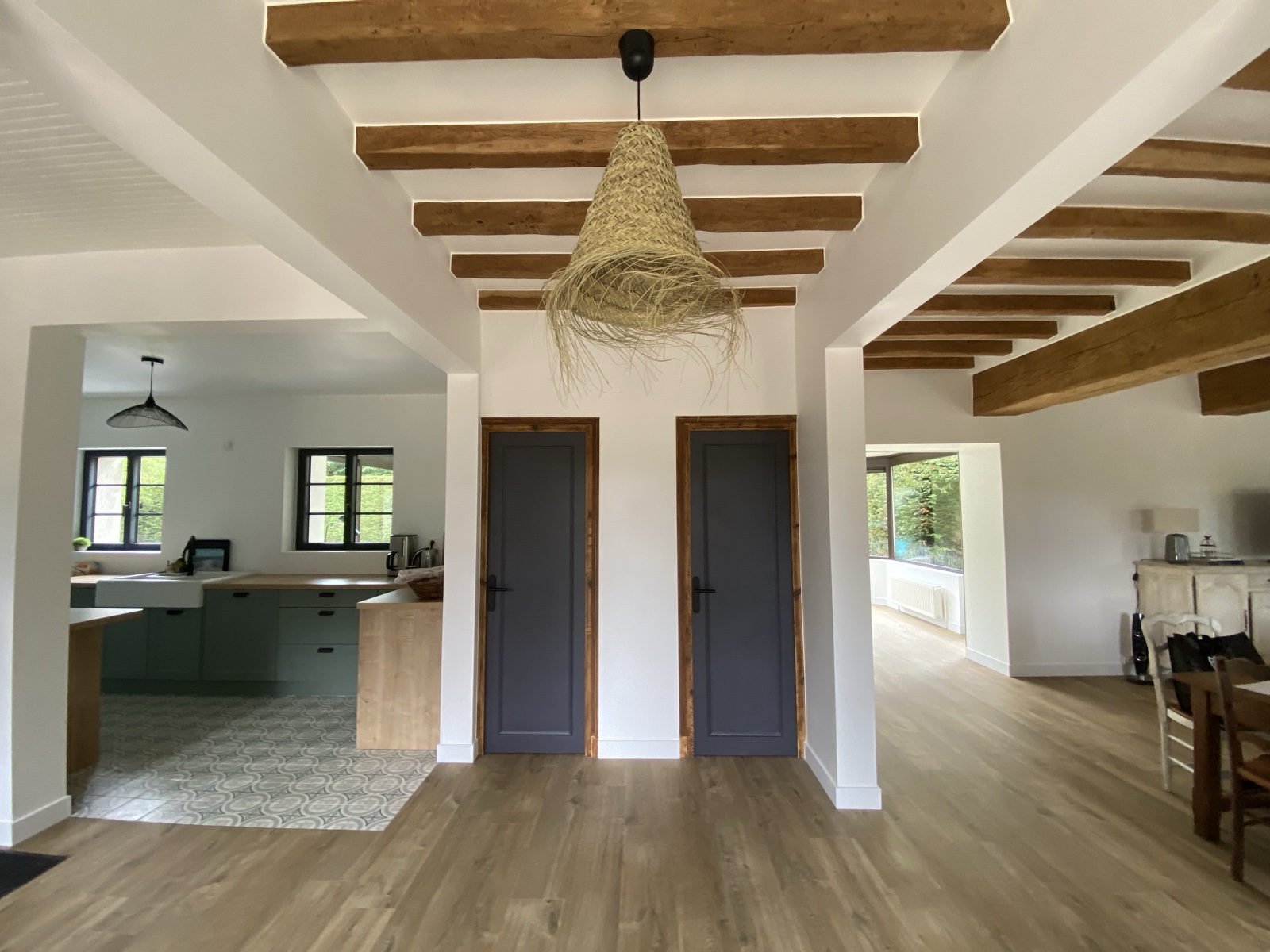 Central hallway under exposed beams, opening to the kitchen on one side and the salon on the other